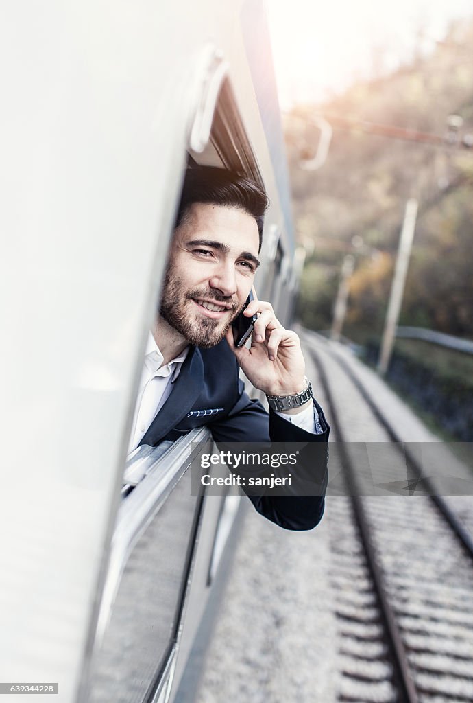 Businessman Talking on The Phone Looking Through Train Window