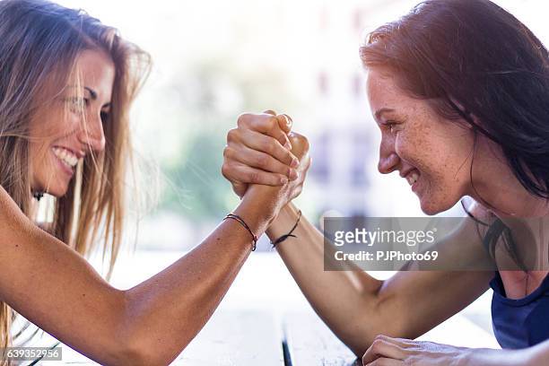 two girls playing arm wrestling - rivaliteit stockfoto's en -beelden