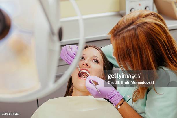 dentist using dental equipment on woman's teeth - dental cleaning stock pictures, royalty-free photos & images