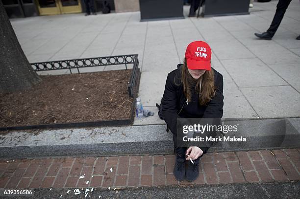 Protestor wears a "Fuck Trump" hat while smoking a cigarette after the inauguration of Donald Trump as the 45th President of the United States...
