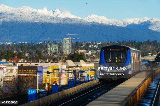 canada line running through richmond and vancouver city with snow capped mountain - vancouver canada stockfoto's en -beelden