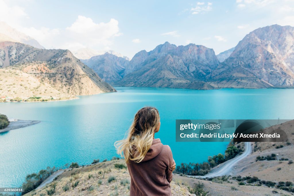 Young woman looks out across mountain lake
