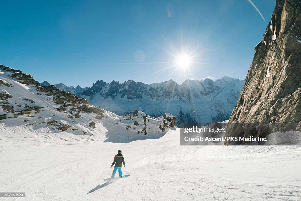 Snowboarder descends empty mountain slope