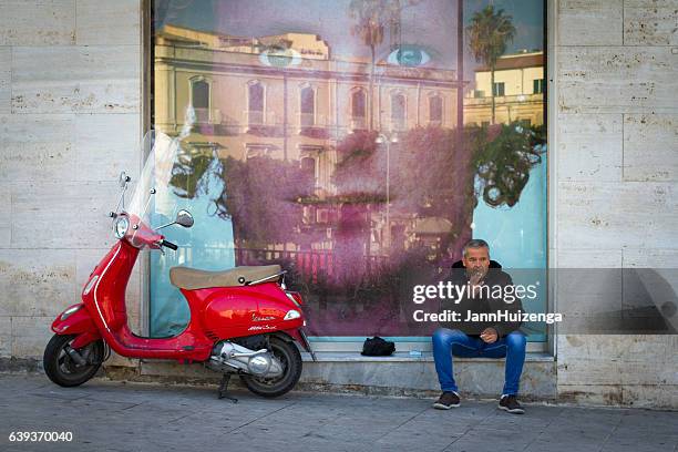 sicily: man sits smoking near vintage vespa and huge advertisement - designer label stock pictures, royalty-free photos & images