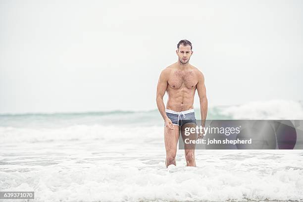 man wearing grey swim shorts in the sea. - swimming shorts stock pictures, royalty-free photos & images