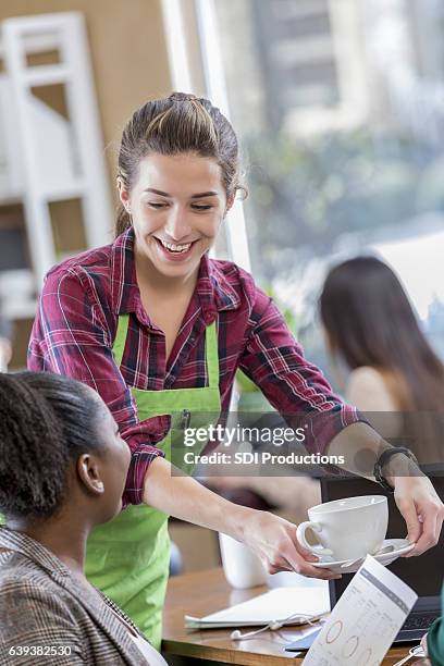 cheerful female server serves coffee to business woman - serveur restaurant stock pictures, royalty-free photos & images