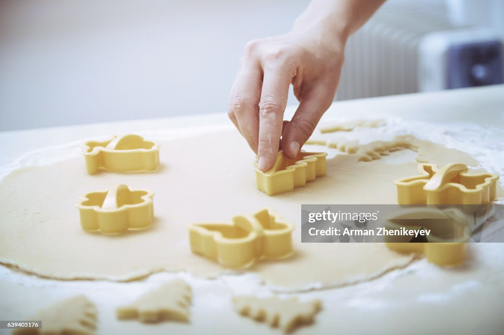 Woman with pastry cutter making holiday cookies