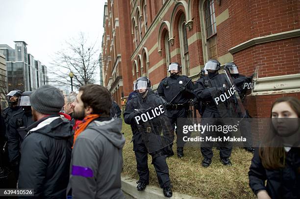 Police officers wearing tactical gear form a barrier with riot shields to prevent the movement of protestors after the inauguration of Donald Trump...