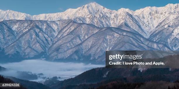 snowy mountains and hakuba village covered with clouds - hakuba fotografías e imágenes de stock