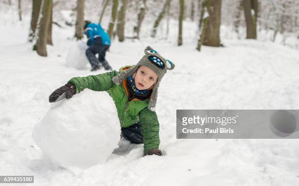 boy making snowman outdoors - schneemann bauen stock-fotos und bilder
