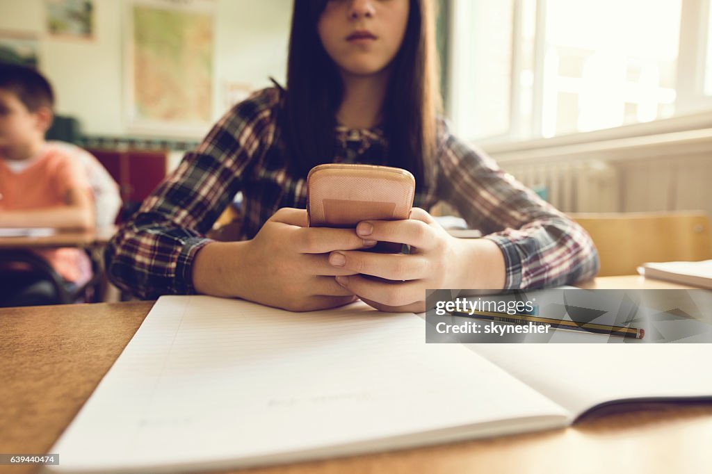 Primo tempo di studentessa che usa il cellulare in classe.