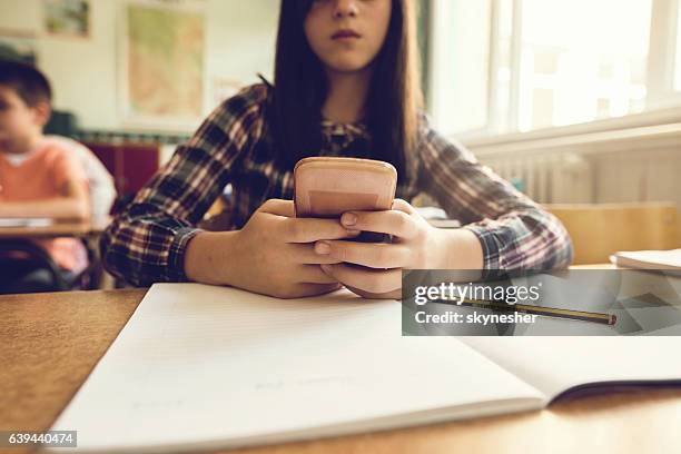 close up of schoolgirl using mobile phone in the classroom. - kid using phone stock pictures, royalty-free photos & images