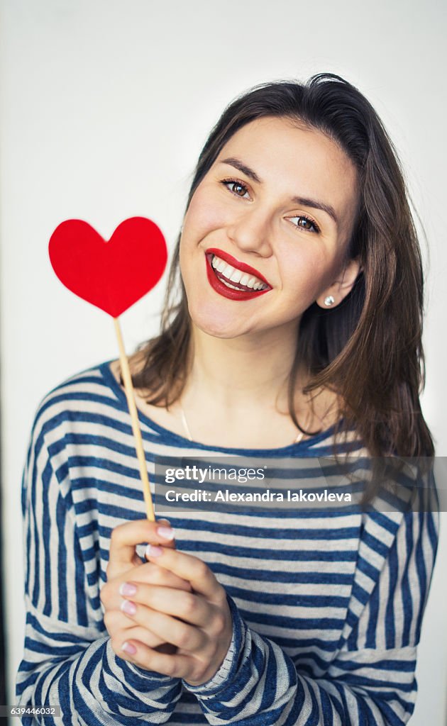 Beautiful young woman holding paper heart