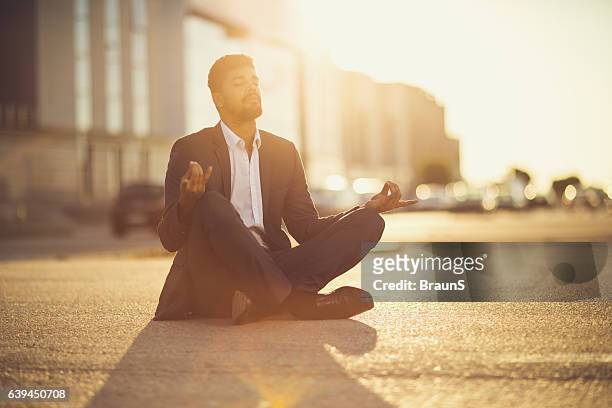 african american businessman in lotus position at sunset. - businessman meditating stock pictures, royalty-free photos & images