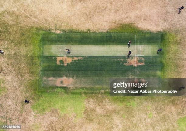 aerial view of people playing cricket in ground. - cricket pitch stock pictures, royalty-free photos & images