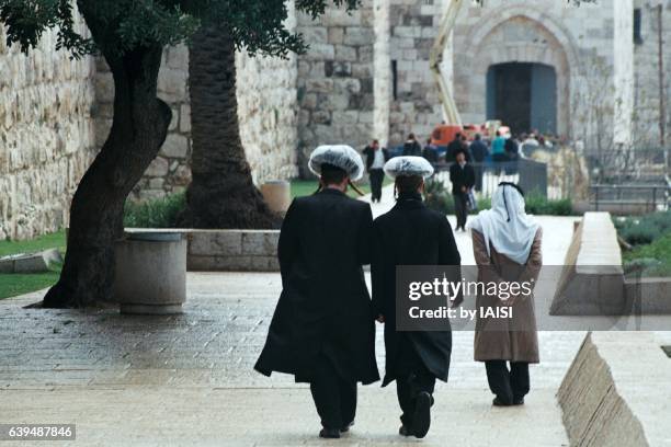 along the walls of the old city, haredi jews wearing shtreimels and arab old man - haredi judaism stock pictures, royalty-free photos & images