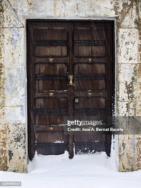 door of ancient wood in the street of a people of medieval  construction, covered of snow in winter - doors of the 21st century ストックフォトと画像