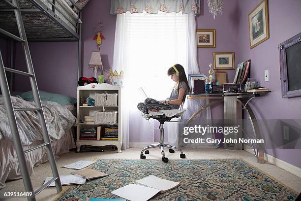 girl in her bedroom using laptop with headphones - norman window fotografías e imágenes de stock