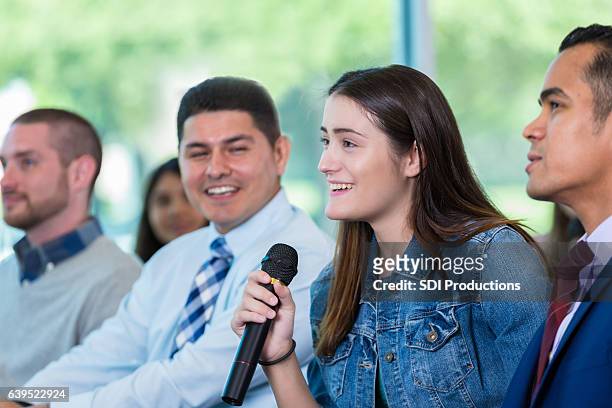 young woman asks question during town hall meeting - local politics stockfoto's en -beelden