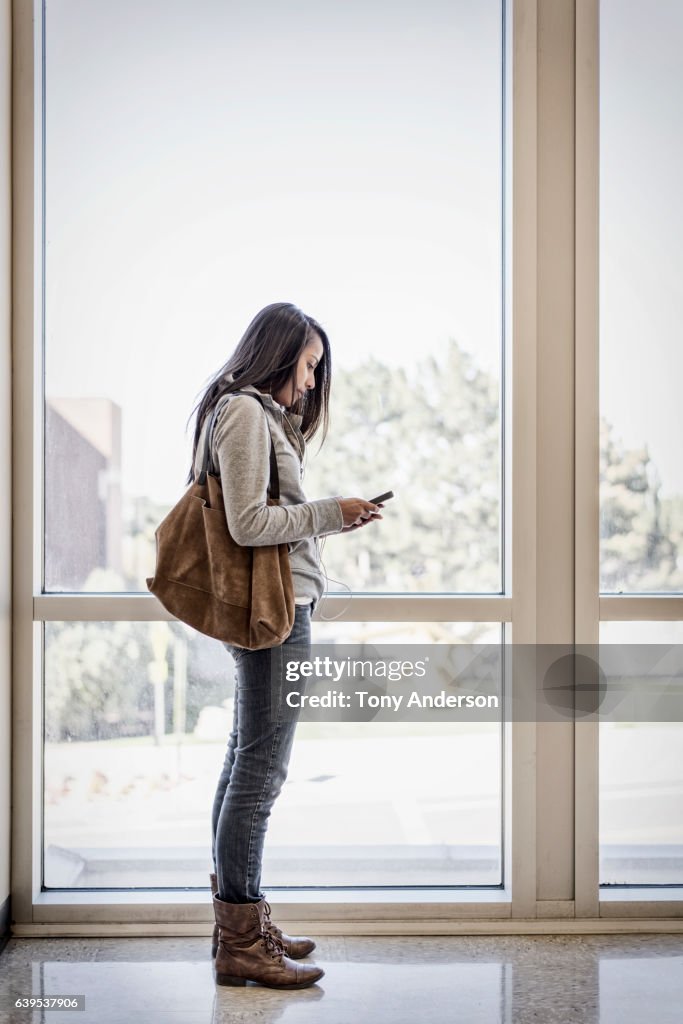 Young Native American woman with phone in public building