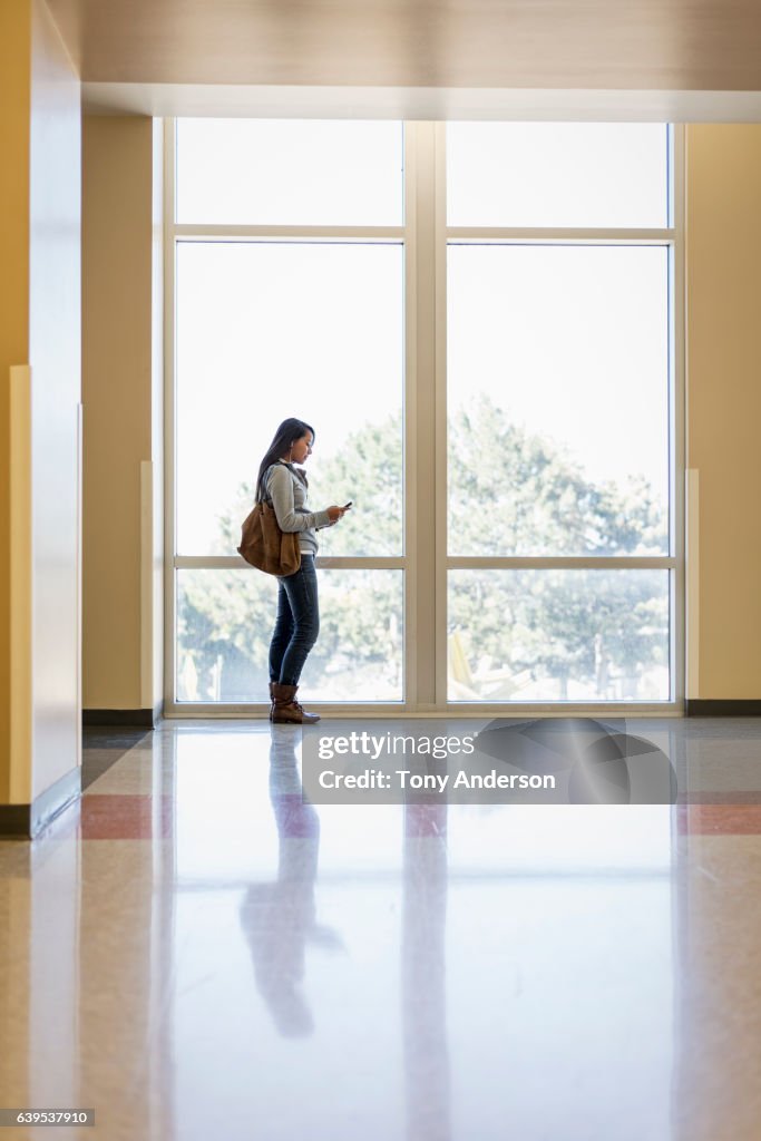 Young Native American woman with phone in public building