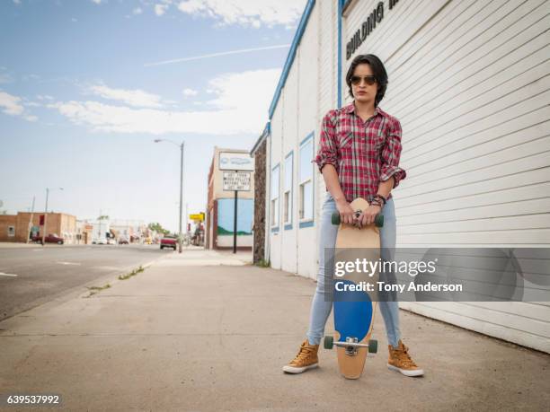 young hispanic woman with skateboard small town - mexican american stock pictures, royalty-free photos & images