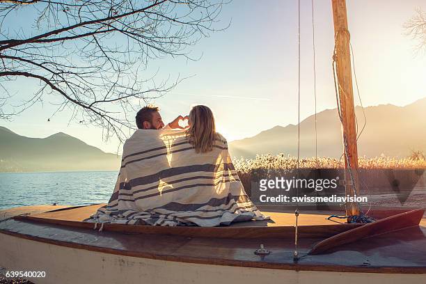 young couple by the lake making heart shape finger frame - young couple beach stock pictures, royalty-free photos & images