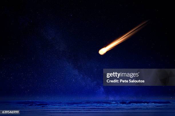 meteor in night sky falling over ocean - comet fotografías e imágenes de stock