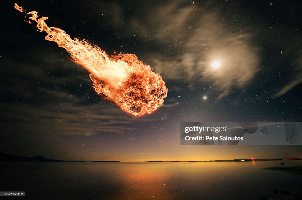 Meteor falling through starry night sky over water