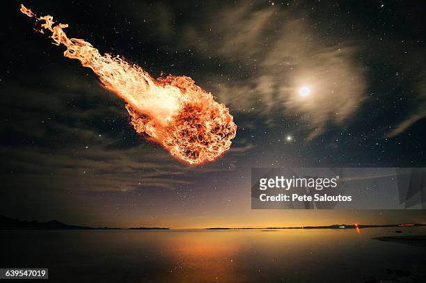 meteor falling through starry night sky over water - meteor stock pictures, royalty-free photos & images