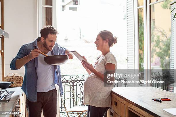 husband and wife cooking at home - pregnant couple stock-fotos und bilder