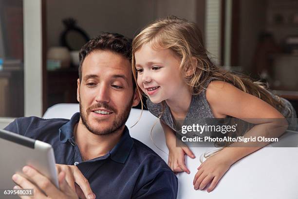 man showing daughter video streaming on digital tablet - easy solutions fotografías e imágenes de stock