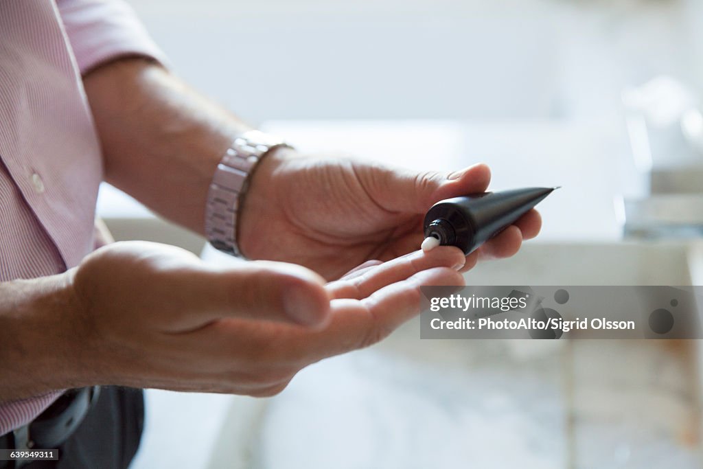 Man applying moisturizer to hands, cropped