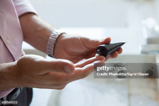 man applying moisturizer to hands, cropped - creme tube imagens e fotografias de stock