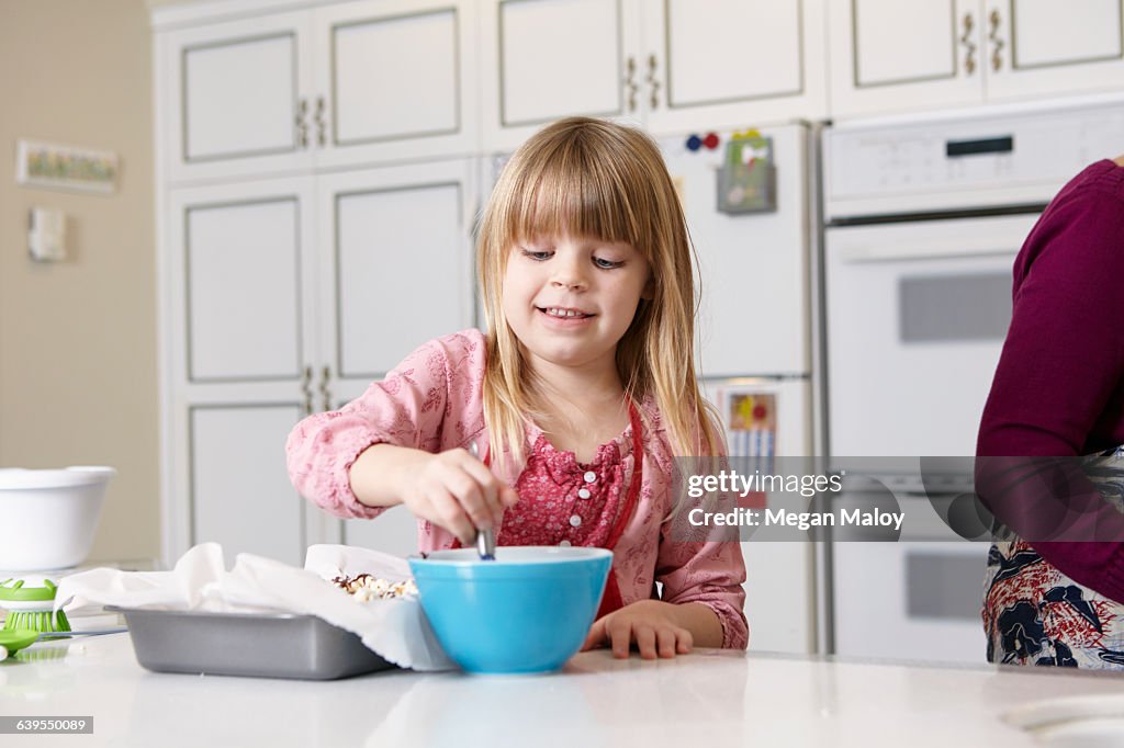 Girl mixing cake at kitchen counter