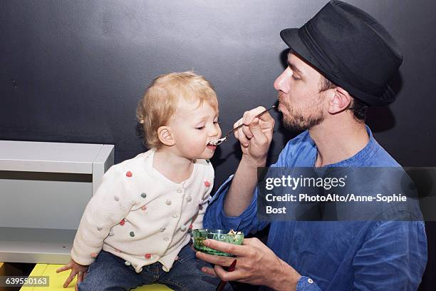 father spoon feeding toddler - ice cream bowl side view stock pictures, royalty-free photos & images