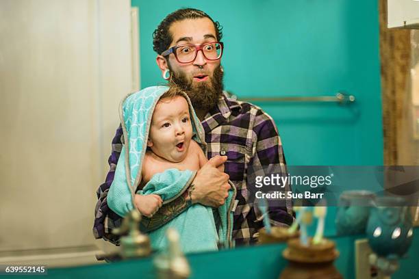 mirror image of young man and baby son pulling faces in bathroom - funny face baby stock pictures, royalty-free photos & images