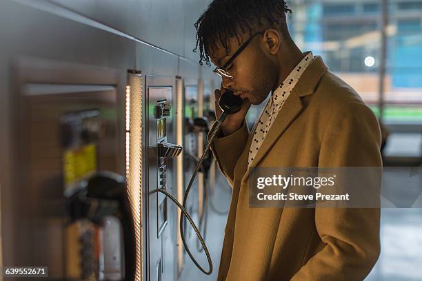 serious young businessman talking on train station pay phone - pay phone stock pictures, royalty-free photos & images