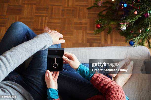 overhead view of couple holding xmas necklace gift on living room sofa - friendship necklace stock-fotos und bilder