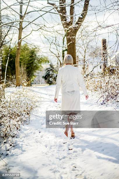 young woman wearing white, walking in winter landscape, rear view - stiletto ストックフォトと画像