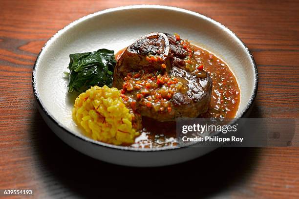high angle view of ossobuco with side dish of vegetables in shallow bowl - osso bucco stock-fotos und bilder