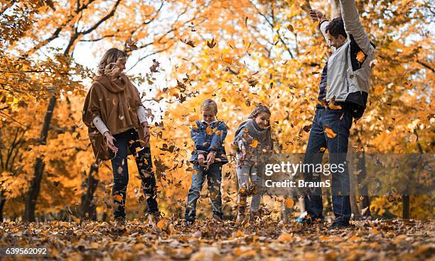 playful family throwing autumn leaves in the park. - throwing leaves stock pictures, royalty-free photos & images