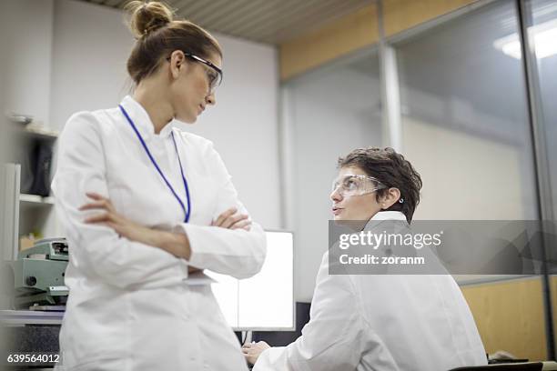 female engineers talking in lab - biochemie stockfoto's en -beelden