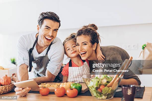 hermosa pareja joven con chica pequeña en la cocina - family at kitchen fotografías e imágenes de stock