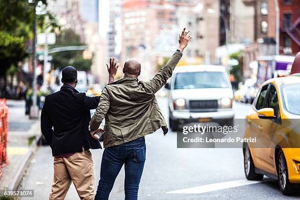 men couple hailing a taxi in new york - hail stock pictures, royalty-free photos & images