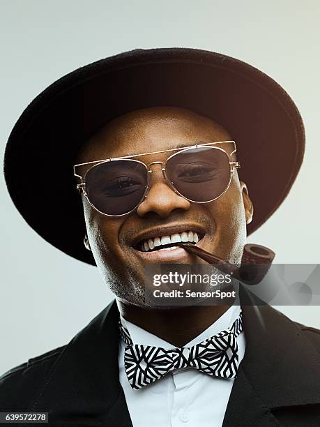 portrait of happy man with smoking pipe in mouth - black suit sunglasses stock pictures, royalty-free photos & images