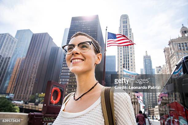 young woman in downtown chicago against us flag - chicago lifestyle stock pictures, royalty-free photos & images