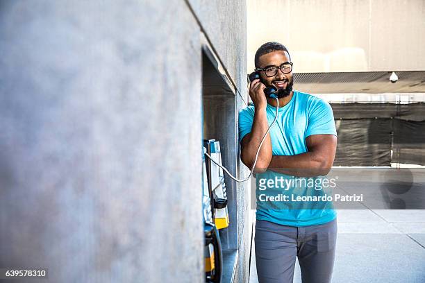 man having a call on a phone booth in downtown - pay phone stockfoto's en -beelden