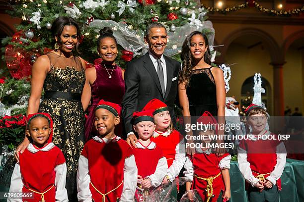 President Barack Obama, center right, first lady Michelle Obama, left, and daughters Sasha, center left, and Malia, right, pose with "elves" prior to...