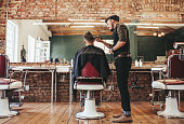 Hairstylist serving client at barber shop